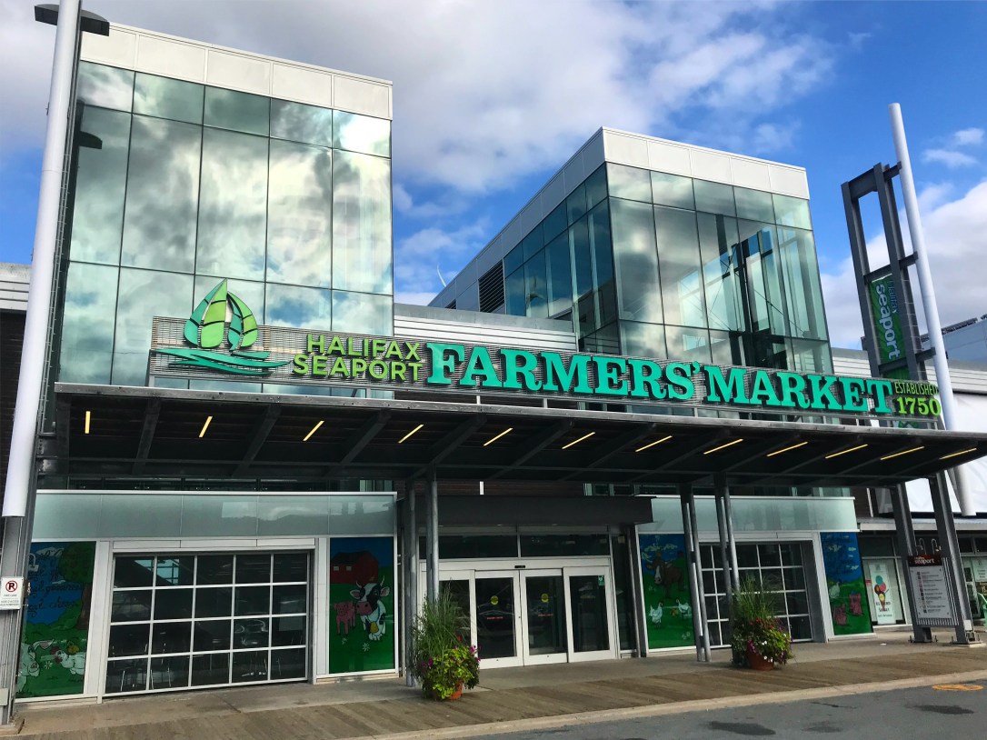 A glass building with a sign the reads Halifax Seaport Farmers'Market.